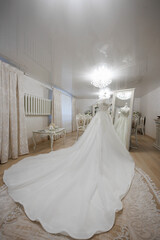 A bride is getting ready for her wedding in a room with a large mirror. The room is decorated with white curtains and furniture, giving it a clean and elegant atmosphere