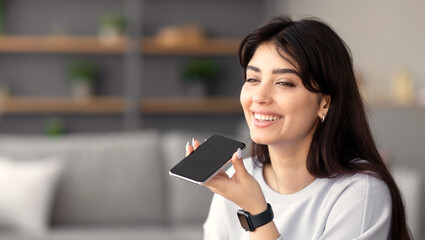 Digital Speaker Application. Portrait of young smiling woman sitting at table, talking on mobile...