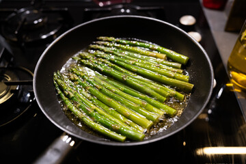 Fresh asparagus being cooked in a pan in the kitchen