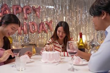 Happy friends with tasty cake and glasses of sparkling wine celebrating birthday indoors