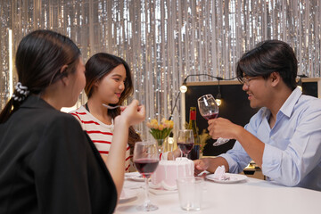 Happy friends with tasty cake and glasses of sparkling wine celebrating birthday indoors