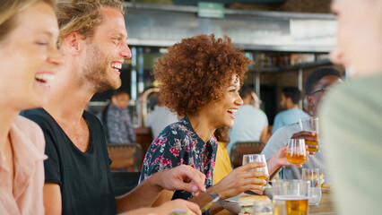 Group Of Young Friends Meeting For Drinks And Food In Restaurant Or Bar