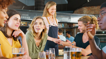 Customer Making Contactless Payment On Mobile Phone To Waitress For Meal In Restaurant