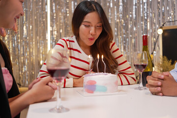 Happy friends with tasty cake and glasses of sparkling wine celebrating birthday indoors

