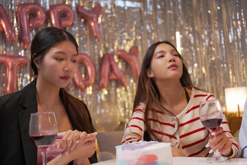 Happy friends with tasty cake and glasses of sparkling wine celebrating birthday indoors

