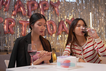 Happy friends with tasty cake and glasses of sparkling wine celebrating birthday indoors

