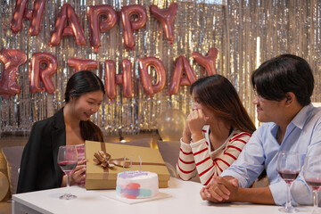 Happy friends with tasty cake and glasses of sparkling wine celebrating birthday indoors

