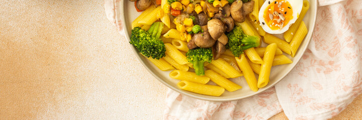 Delicious breakfast, pasta with fried mushrooms and broccoli, green peas and corn, fresh mix salad with radishes with seeds, top view, banner