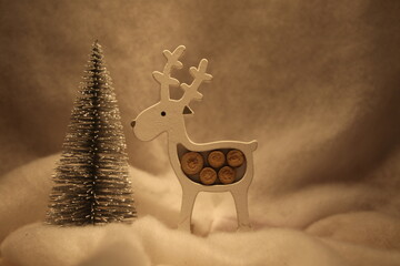 Christmas postcard with a reindeer and a tree, with snow in the background and warm light. Defocused golden background lights. Reindeer with dark silhouette