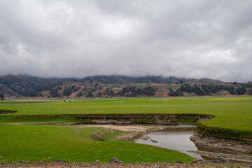 Beautiful landscape of green meadow and mountains surrounded by fog on a cloudy day, landscape in Bolivia.
