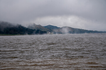 A lake surrounded by a pine forest covered by morning fog, Corani bolivia