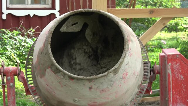 A concrete mixer is mixing concrete in the farmyard