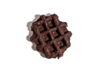 A chocolate waffle sits on a white background. The waffle is covered in chocolate and has a square shape Sweet pastries isolated on white background.