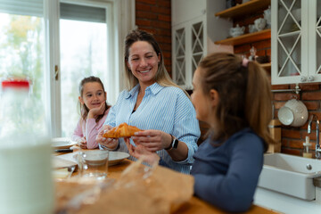 Morning breakfast preparation as mother and daughters gather around counter, working together amid fresh produce and kitchen supplies