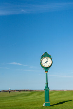 Man playing golf on a golf course with large clock 