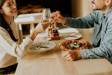 Couple enjoying a romantic dinner together in a cozy restaurant, celebrating with a toast over delicious cuisine on a warm evening