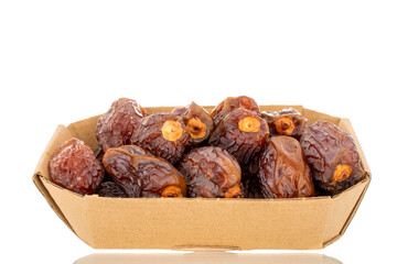 Dried sweet dates in a paper plate, isolated on a white background, close-up.