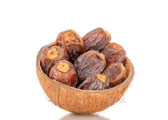 Dried sweet dates in coconut shell, isolated on white background, close-up.
