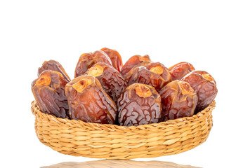 Dried sweet dates in a straw plate, isolated on a white background, close-up.