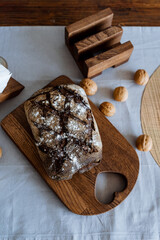 On a beautifully crafted wooden cutting board with an elegantly designed heartshaped handle, there sits a fresh loaf of bread, ready to be sliced and enjoyed as a staple food