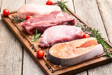 Mix of raw meat and fish . Salmon , beef , pork , chicken staek . Top view