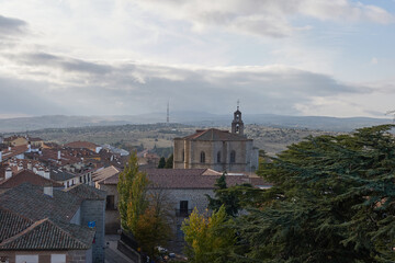 Fototapeta premium City on the Horizon – A distant skyline framed by rolling hills, kissed by a soft, cloudy light