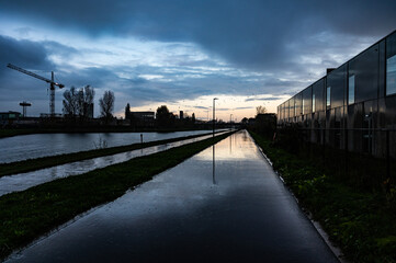 Obraz premium Colorful sunset and rain reflections at the industrial banks of the canal in Ruisbroek, Sint Pieters Leeuw, Belgium