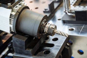 A machine is cutting a piece of metal with a drill bit