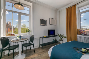 A magnificent interior of a studio apartment with a properly distributed space. Stylish .furniture. Windows overlooking the courtyard on a summer day.