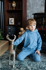 In a peaceful and serene setting, a young boy dressed in a soft blue hoodie kneels beside a...