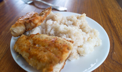 Fried fish and rice and plates on wooden table close-up
