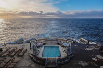 Breathtaking sunset sunrise ocean view from outdoor teak pool promenade deck of ocean liner at sea during transatlantic crossing to New York