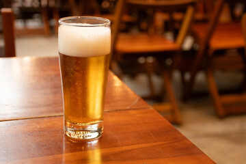 glass of lager beer on bar table with blurred background