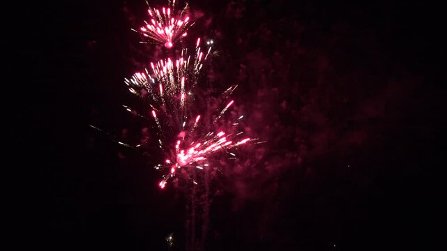 Firework display in the dark sky as beautiful colours light up a celebration. New year and 4th July party background 4K