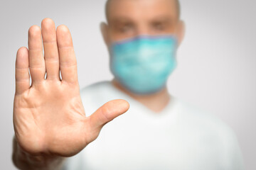 Stop Coronavirus. Unrecognizable Man In Medical Mask Gesturing Stop Standing Over Gray Background...