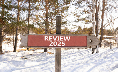 Planning review 2025 new year symbol. Concept words Review 2025 on beautiful wooden old retro vintage road sign. Beautiful winter forest background. Business review 2025 new year concept. Copy space.