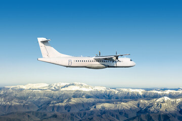 White passenger turboprop airplane fly over snow covered mountains