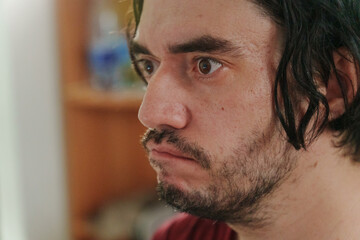 Obraz premium A close-up of a man with tousled hair, revealing his curious expression in a vibrant, colorful setting during a lively gathering