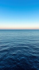Obraz premium Calm ocean horizon at sunset with clear blue sky in coastal view