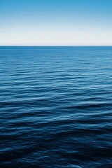 Fototapeta premium Peaceful blue ocean waves under a clear sky at midday