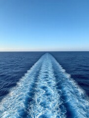 Gentle ocean waves trail behind a boat under clear blue sky