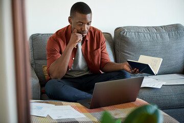 Young African man working remotely from home on his sofa