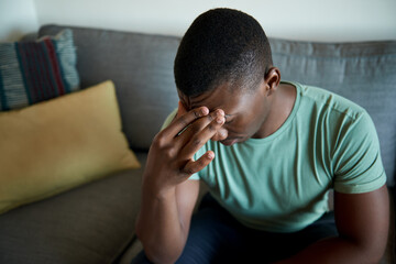 Obraz premium Young African man sitting on his sofa looking distraught
