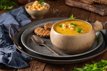 Pumpkin and chickpeas soup on brown rustic wooden background.