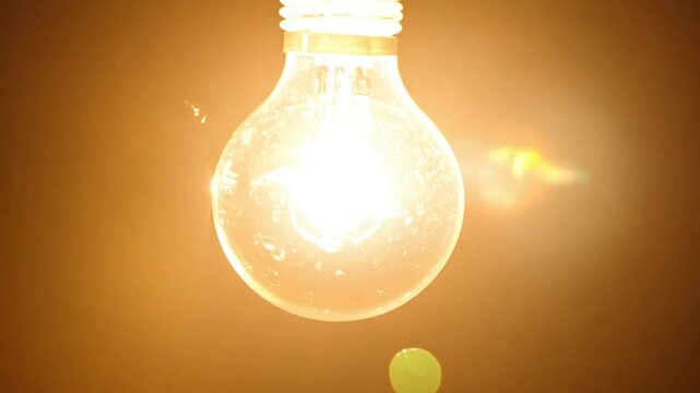 Close-up of incandescent light bulb lighting up and exploding, symbolizing ideas and innovation