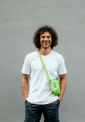 Smiling man with curly hair wearing casual white shirt and green crossbody bag