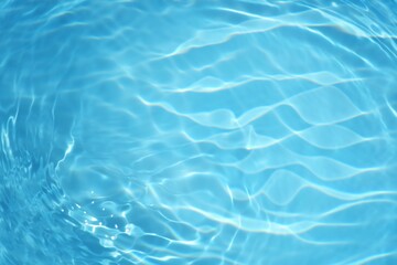 Blue water with ripples on the surface. Defocus blurred transparent blue colored clear calm water surface texture with splashes and bubbles. Water waves with shining pattern texture background.