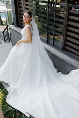 Naklejka premium A woman in a white wedding dress is standing on a staircase. She is smiling and looking at the camera