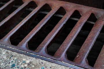 abstract rusty metal water drain manhole cover on pavement road down the drain metaphor grunge...