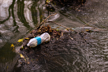Obraz premium rubbish bottle floating in creek addressing environment and pollution theme